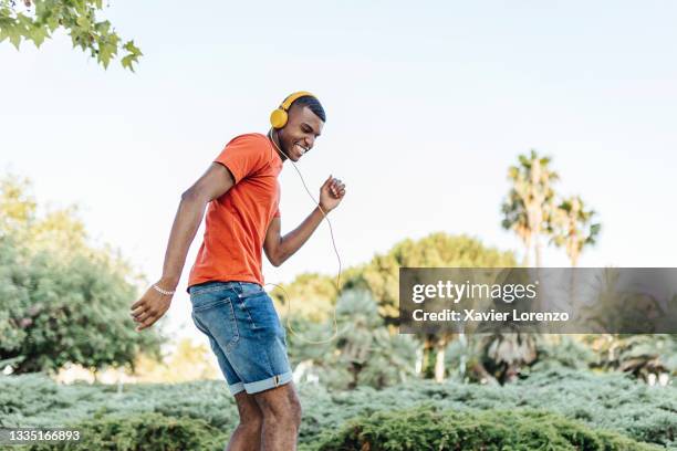 cheerful brazilian man dancing while listening to music in city park - guy dancing music dynamic stock pictures, royalty-free photos & images