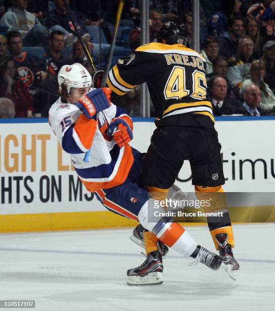 David Krejci of the Boston Bruins hits P.A. Parenteau of the New York Islanders at the Nassau Veterans Memorial Coliseum on November 19, 2011 in...