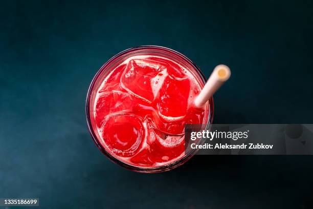 strawberry berry soft drink or cocktail with ice, with a straw in a glass glass on a wooden table in an outdoor cafe or restaurant. - cocktail and mocktail stock pictures, royalty-free photos & images