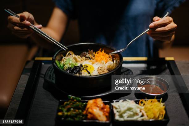 woman eating bibimbap in korean restaurant - korean food stockfoto's en -beelden