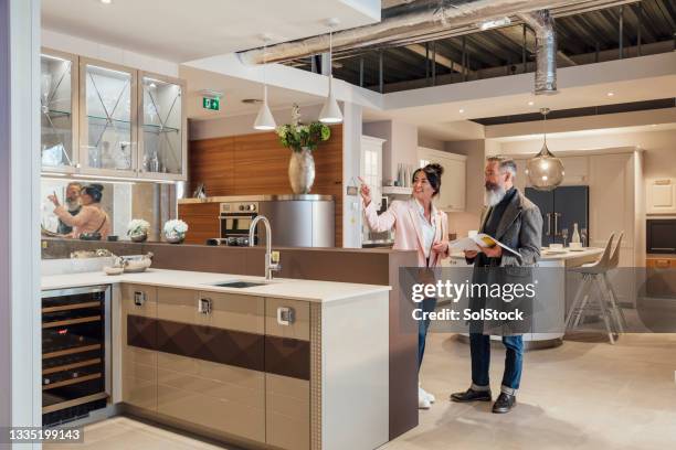 couple viewing kitchen showroom - furniture showroom stock pictures, royalty-free photos & images