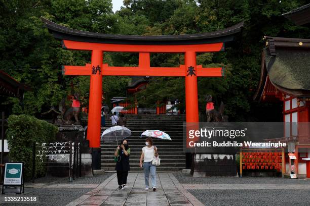 Tourists wearing protective face masks walk in the rain at the Fushimi Inari-taisha shrine, one of Japan's most popular tourist destinations usually...