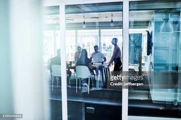 full length shot of a group of young businesspeople having a meeting in their office boardroom - board room stock pictures, royalty-free photos & images