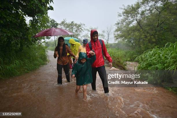 family walking in flowing water in a stream in rains - monzón fotografías e imágenes de stock