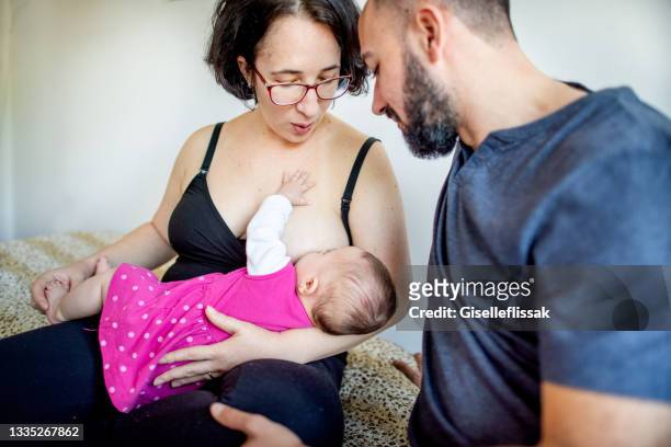 mother breastfeeding her baby while sitting with her husband - dia bildbanksfoton och bilder