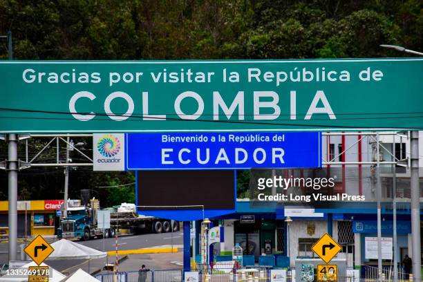 Signs of 'Thank you for visiting Colombia and Welcom to Ecuador' seen close at the Colombia-Ecuador border as drivers of public service vehicles hold...