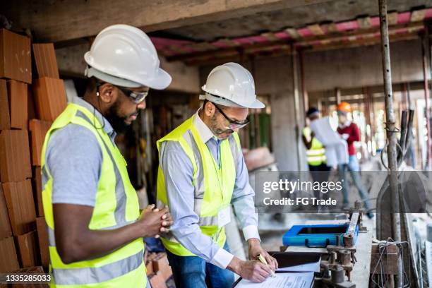 ingegnere e appaltatore che parlano in cantiere - foundations gender equality discussion foto e immagini stock