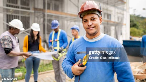 construction electrician standing on a building site with people working in the background - electrician 個照片及圖片檔