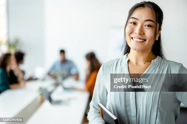 asian businesswoman standing smiling at the camera - employee success stock pictures, royalty-free photos & images