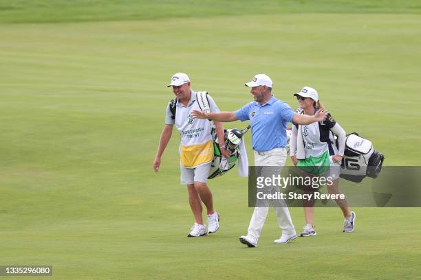 Lee Westwood of England talks with caddies Tim Butler and Helen Storey as they walk up the 13th fairway during the second round of THE NORTHERN...
