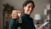 Close up focus on keys, smiling woman Real Estate Agent selling apartment