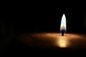 Isolated glowing candle on black background - stock photo