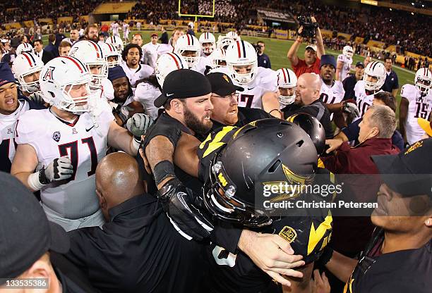 Linebacker Kipeli Koniseti of the Arizona State Sun Devils is held back by security as a fight breaks out at mid field against the Arizona Wildcats...