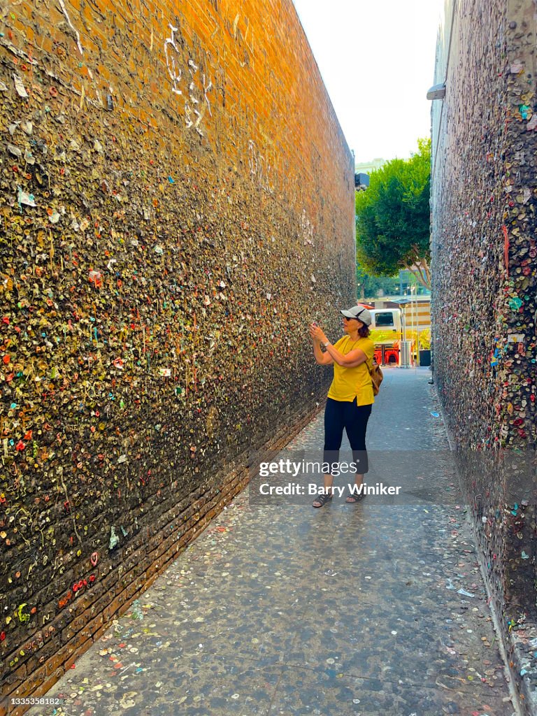 Woman photographing at bubble gum on wall, San Luis Obispo