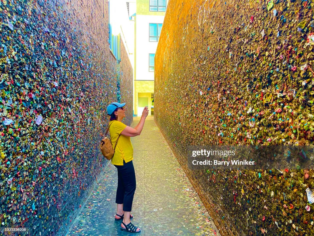Woman photographing at bubble gum on wall, San Luis Obispo