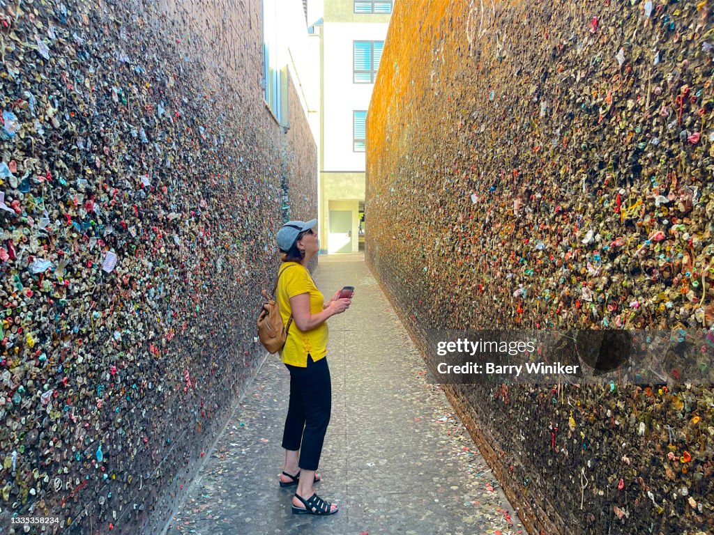 Woman looking at bubble gum on wall, San Luis Obispo
