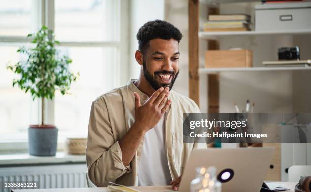 young man with laptop using sign language indoors in office, video call concept. - commercial sign photos et images de collection