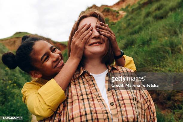 the daughter covered her mother's eyes with her hands. - emotional support stock pictures, royalty-free photos & images