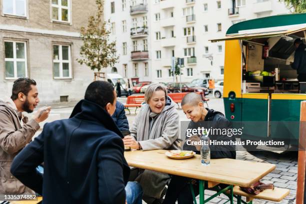 group of friends socializing over meal at food truck eatery - daily life in germany stock-fotos und bilder