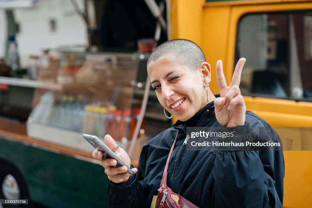 Woman With Shaved Head Giving Peace Symbol