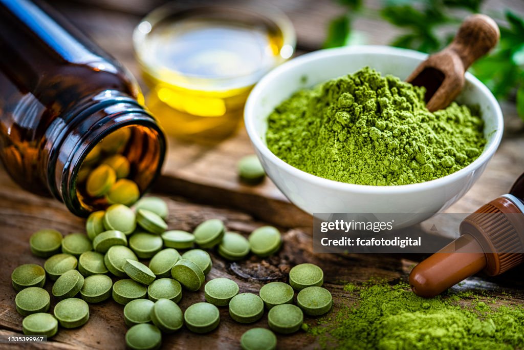 Moringa oleifera em pó e pílulas em mesa rústica