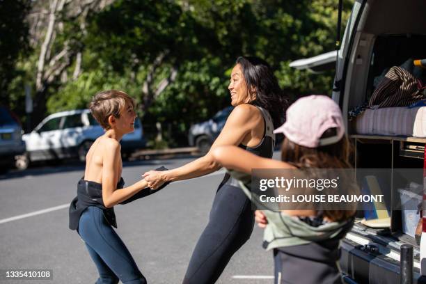 mum playfully helps her son with his wetsuit - family active lifestyle stock pictures, royalty-free photos & images