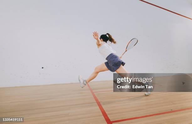 side view asian chinese teenage girl playing squash alone in the court - squash game stock pictures, royalty-free photos & images