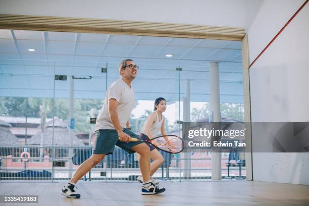 vorderansicht asiatischer squashtrainer vater leitet seine tochter squashsport beim gemeinsamen üben im squashplatz - squash sport stock-fotos und bilder