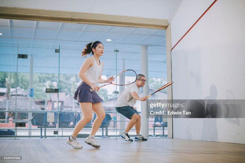Vorderansicht Asiatischer Squashtrainer Vater leitet seine Tochter Squashsport beim gemeinsamen Üben im Squashplatz