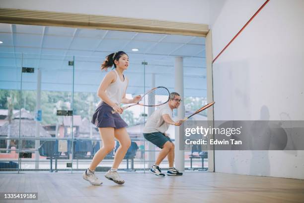 vista frontale asiatico squash allenatore padre che guida insegnare a sua figlia squash sport praticare insieme in campo squash - country club foto e immagini stock