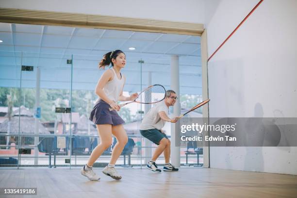 front view asian squash coach father guiding teaching his daughter squash sport practicing together in squash court - squash game stock pictures, royalty-free photos & images