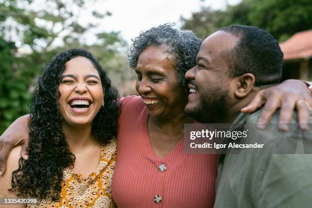 mère étreignant des enfants adultes souriants à l’extérieur. - enfant adulte photos et images de collection