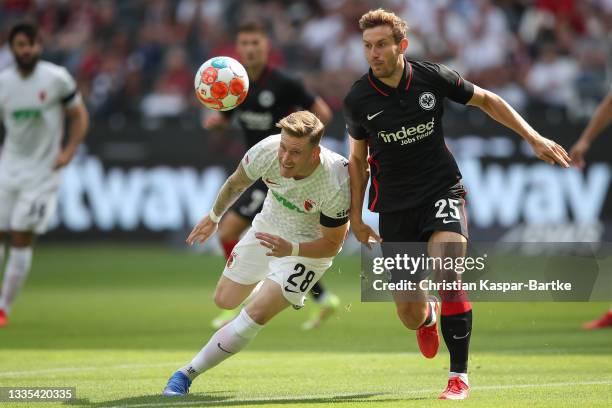 Christopher Lenz of Eintracht Frankfurt is tackled by Andre Hahn of FC Augsburg during the Bundesliga match between Eintracht Frankfurt and FC...