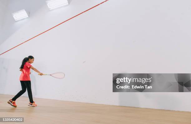 junge asiatische indische squashspielerin, die während der wochenendroutine alleine auf dem squashplatz trainiert - squash racquet stock-fotos und bilder