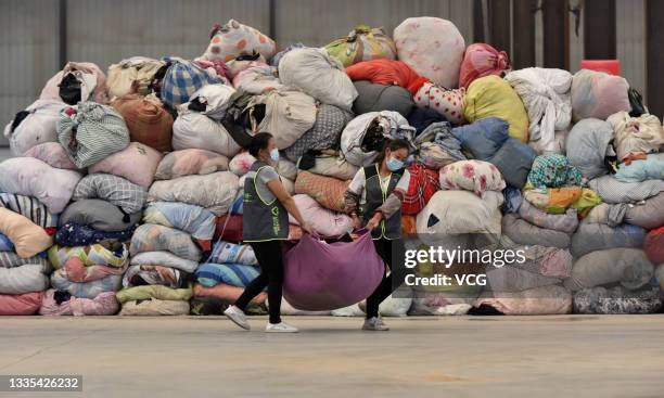 Employees carry a bag of clothes at a waste sorting centre on August 21, 2021 in Taiyuan, Shanxi Province of China.