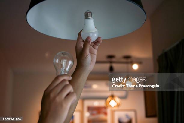 male hands compare an incandescent light bulb and a led lamp - light bulb stockfoto's en -beelden