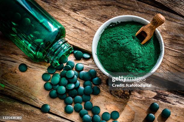 spirulina powder and pills shot from above on wooden table - algae stock pictures, royalty-free photos & images
