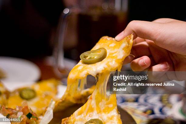 holding cheesy cheese nachos in restaurant - cheese stock pictures, royalty-free photos & images