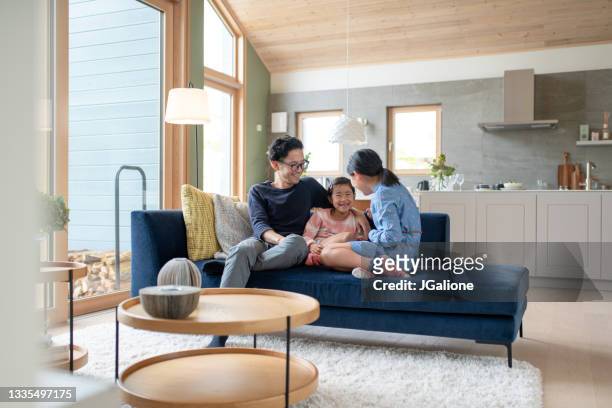 ソファで娘たちとリラックスしている父 - 子供　日本人　笑顔 ストックフォトと画像