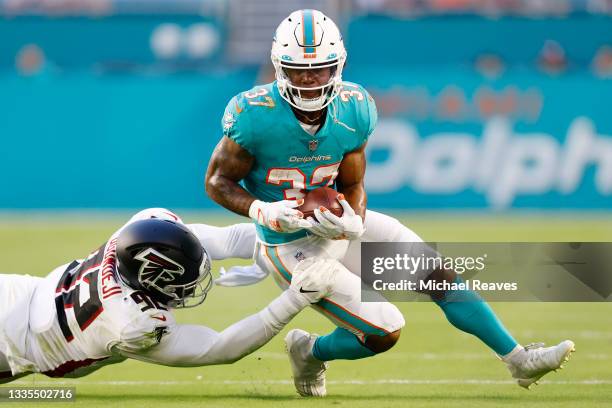 Myles Gaskin of the Miami Dolphins breaks a tackle from Adetokunbo Ogundeji of the Atlanta Falcons during a preseason game at Hard Rock Stadium on...