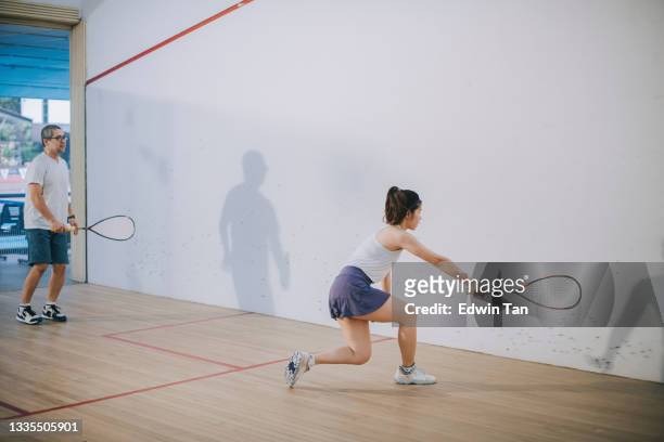 asian squash coach father guiding teaching his daughter squash sport practicing together in squash court - squash racquet stockfoto's en -beelden