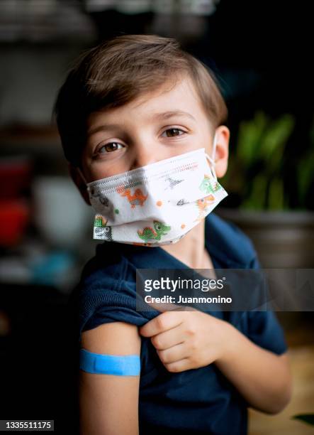 sechsjähriges kind, das kurz nach der impfung sein pflaster zeigt - boys only caucasian ethnicity 6 7 years stock-fotos und bilder