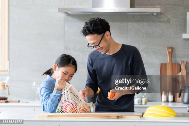 young girl helping her father to unpack groceries - asian man cooking bildbanksfoton och bilder