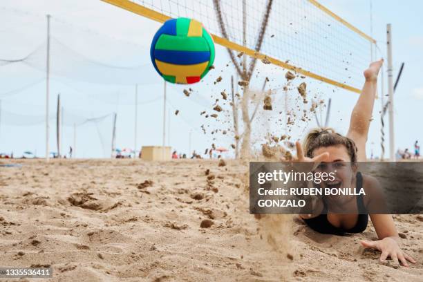 female playing beach volleyball diving to catch ball while looking at camera - girls beach volleyball stock pictures, royalty-free photos & images