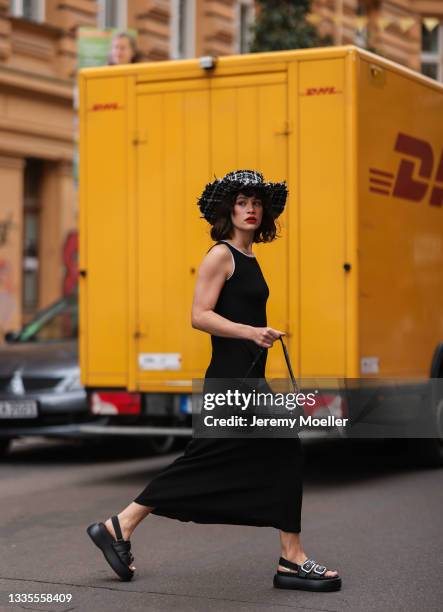 Lea Naumann wearing black Ronni Nicole midi dress, black Bimba y Lola sandals, black and white Baum & Pferdgarten hat and black vintage Dior bag on...