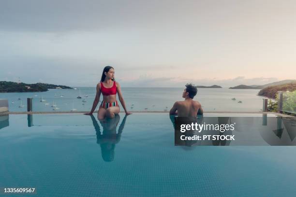 a woman and a man sit and look at each other by the pool. and behind it was a sea with many ships. - phuket ストックフォトと画像