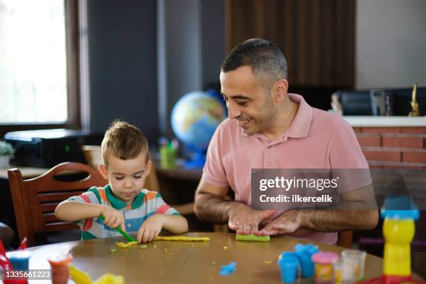 father and little son are molding shape of game doughs at home - male preschooler stock pictures, royalty-free photos & images