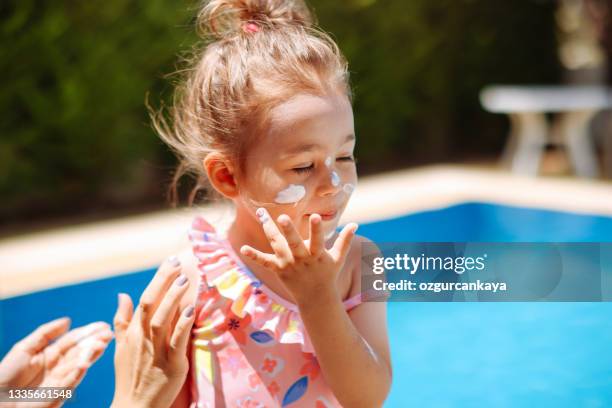 mother put sunblock cream on little daughter face at beach - sun burn stockfoto's en -beelden