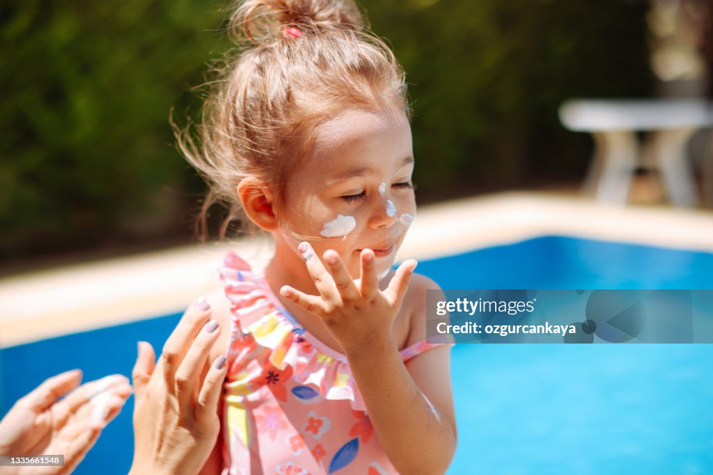 Mãe colocou creme protetor solar no rosto da filhazinha na praia
