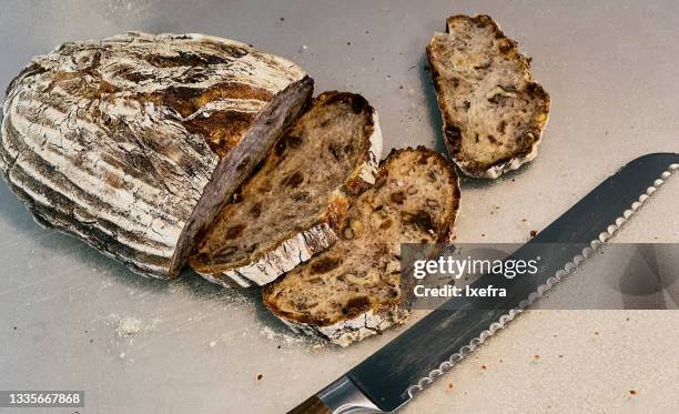 fresh german walnut bread, few slices of it, and a knife on a cutting board. - bread knife stockfoto's en -beelden